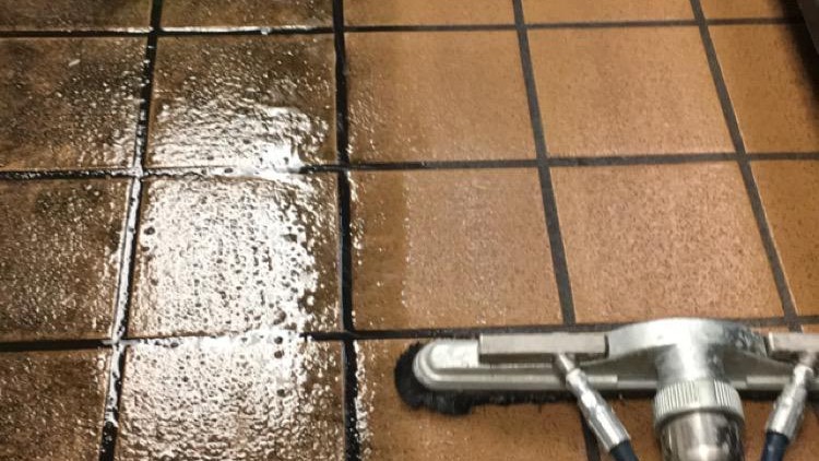 Carpet Cleaning & Home Services in Herriman, Utah - Father and Son Carpet Cleaning A tile floor is being cleaned, showcasing the superior quality of Home Services in Herriman, Utah; the left side remains dirty and wet, while the right side is clean and dry as a professional cleaning tool passes over the surface—demonstrating results just as impressive as expert carpet cleaning.