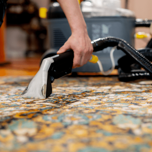 Why Carpet Stretching Matters More Than You Think - Father and Son Carpet Cleaning A person uses a carpet cleaning machine to clean a patterned carpet, as part of regular carpet maintenance.