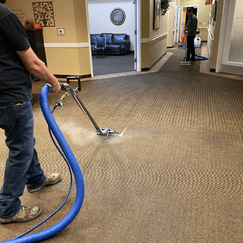 Why Carpet Stretching Matters More Than You Think - Father and Son Carpet Cleaning Two people use professional carpet cleaning equipment for thorough carpet maintenance on the hallway floor of a commercial building.