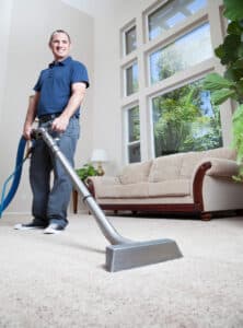 A man performing carpet cleaning with stain removal in a living room.