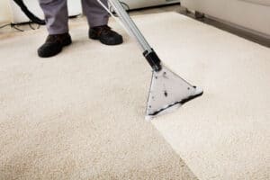 A man performs carpet cleaning in a living room using stain removal techniques.